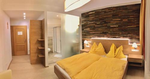 ein Schlafzimmer mit einem gelben Bett und einer Ziegelwand in der Unterkunft Gasthof-Hotel zur Linde in Yspertal