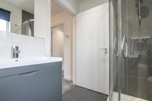 a white bathroom with a sink and a shower at Martello View - 3 Bedroom Holiday Home - Llanreath in Pembroke Dock