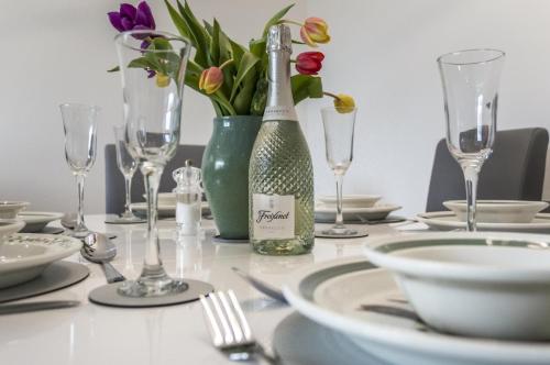 a table with a bottle of wine and a vase of flowers at Martello View - 3 Bedroom Holiday Home - Llanreath in Pembroke Dock