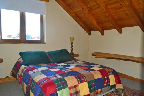 a bedroom with a colorful bed with two windows at Lodge Tikilen Caviahue in Caviahue