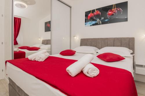 a bedroom with two beds with red pillows at Holiday Home Maslina in Tugare
