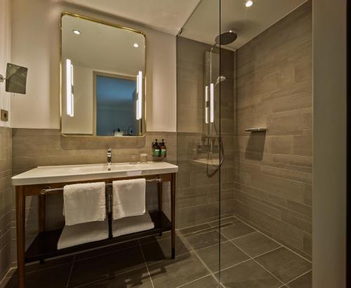 een badkamer met een wastafel en een douche bij voco The Hague, an IHG Hotel in Den Haag