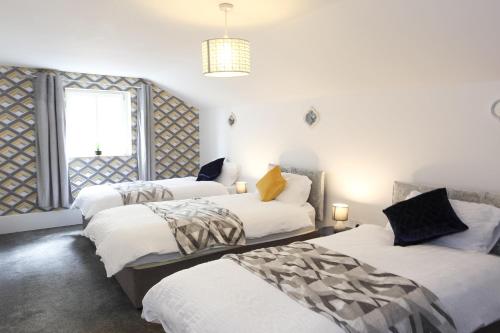 3 Betten in einem Zimmer mit weißen Wänden und einem Fenster in der Unterkunft Contractor & Leisure Stays- FREE Parking with Great Location in Pembrokeshire