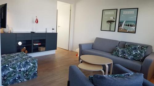 salon z niebieską kanapą i stołem w obiekcie Løkken centrum ferielejlighed-apartment 4F w mieście Løkken