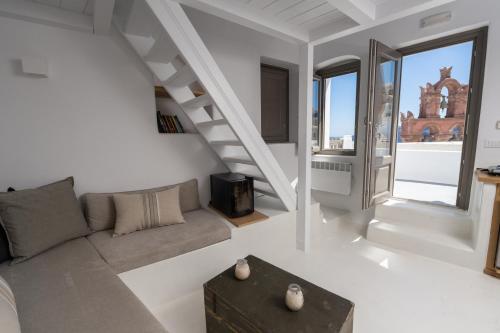 een witte woonkamer met een bank en een trap bij Astrea Suites Notus Dome House in Oia