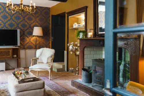 a living room with a fireplace and a chair at Logement Onze Chambres & Gîtes in Raissac-dʼAude