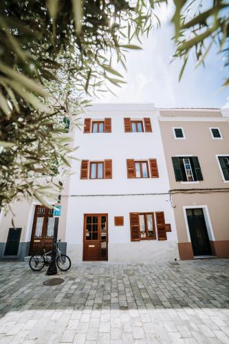 a large white building with brown doors and windows at Murada hotel in Ciutadella