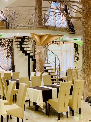 a dining room with tables and chairs and a staircase at VitaPark Stariy Dub in Truskavets