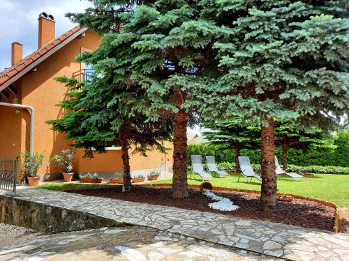 a group of trees and chairs in a yard at Harmónia Vendégház in Balatonalmádi