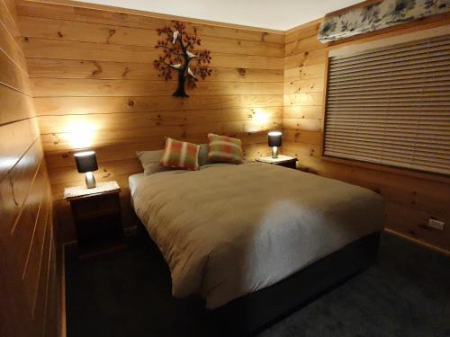 羅托魯阿的住宿－Folia Domus NZ, Redwoods, MBT，一间卧室配有一张带两盏灯的床和一扇窗户。