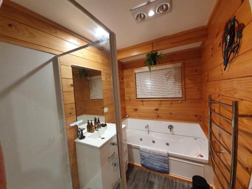 a bathroom with a tub and a sink and a bath tub at Folia Domus NZ, Redwoods, MBT in Rotorua