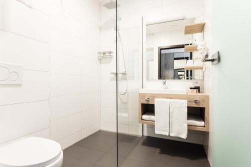 a white toilet sitting next to a white sink in a bathroom at Hotel Smart Liv'in in Böheimkirchen