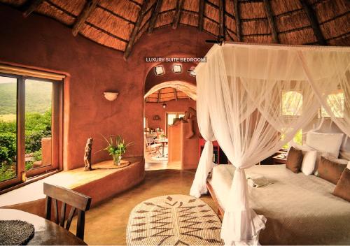 a bedroom with a bed with curtains and a table at Leshiba Wilderness in Louis Trichardt