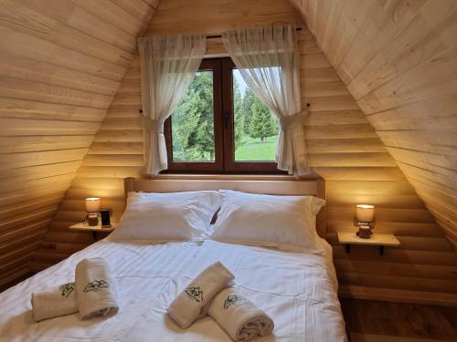a bed in a wooden room with a window at Hedonist Village in Žabljak
