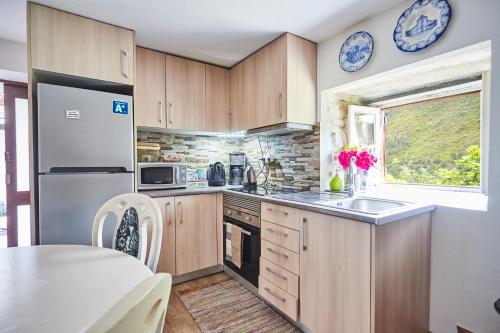 a kitchen with wooden cabinets and a table and a window at Cottage da Paradinha: Passadiços do Paiva - Arouca in Paradinha