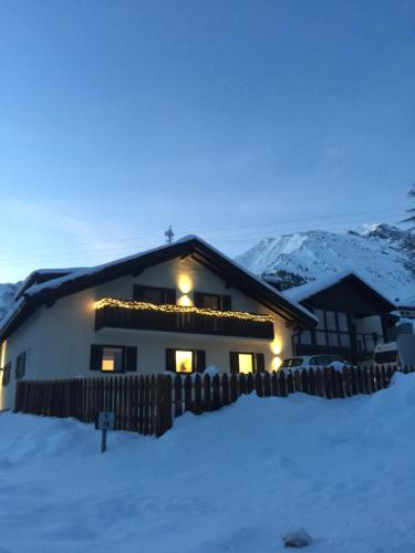 a house in the snow with lights on it at Dorfblick Appartements & Rooms in Senales