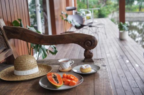 une table avec deux assiettes de fruits et un chapeau dans l'établissement Mooi Lake House Luxury Villa, à Malabar