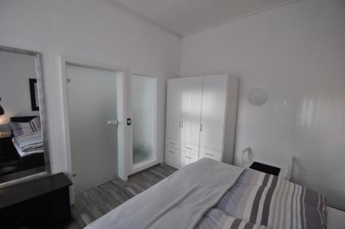 um quarto branco com uma cama e um espelho em Feriendomizil Auszeit em Wernigerode