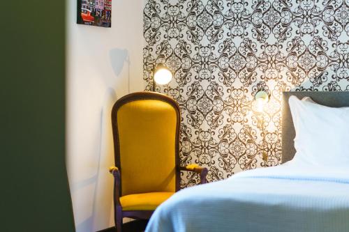 a bedroom with a yellow chair next to a bed at Logement Onze Chambres & Gîtes in Raissac-dʼAude