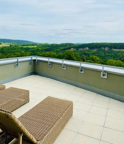 a balcony with wicker chairs and a view of the countryside at Hotel Bei Gretel, Wellness & Ayurveda in Struppen-Siedlung