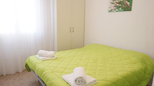 um quarto com uma cama verde e toalhas em APPARTAMENTO SAN MARCO em Lido di Jesolo