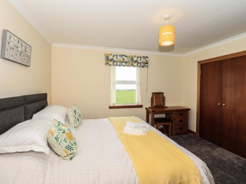 a bedroom with a bed with a yellow blanket on it at Challochmun Bungalow in Newton Stewart