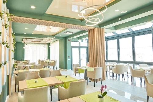 a restaurant with green walls and tables and chairs at Hotel Azaleea Mamaia Nord in Mamaia Nord