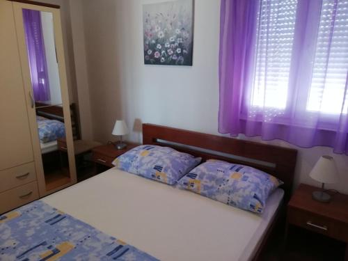a bedroom with a bed with two pillows and purple curtains at Apartment in Sevid with Seaview, Balcony, Air condition, WIFI (4755-4) in Sevid
