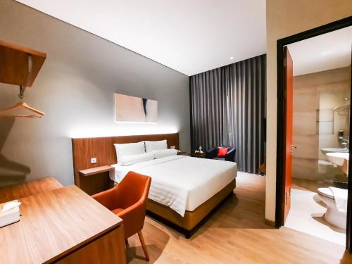 um quarto de hotel com uma cama e uma casa de banho em Votel Krakatau Boutique Hotel Semarang em Semarang