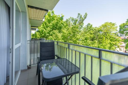 a balcony with a table and chairs and trees at Seaside Breeze Stylish Apartment Balcony & Parking by Renters in Międzyzdroje