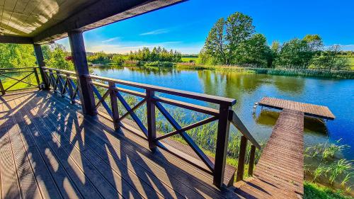 a wooden deck with a bench on the side of a river at Holiday House "Brūklenes" in Talsi