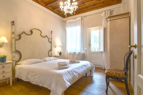 a bedroom with a large white bed and a chair at Casa Michelangelo & Giotto - Tintori apt in Florence