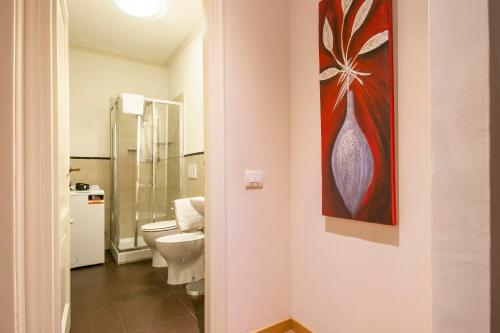 a bathroom with a toilet and a painting on the wall at Casa Michelangelo & Giotto - Tintori apt in Florence