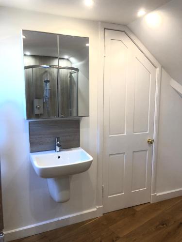 a bathroom with a sink and a mirror and a door at Castle Nook in Kelso