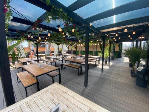 an outdoor patio with wooden tables and benches at Snoozebox Olympic Park in London