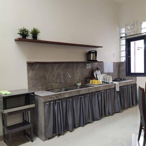 a kitchen with a long counter with a sink at Tropical Cozy House in the heart of Medan in Medan
