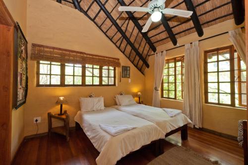 a bedroom with a large bed and two windows at Greenfire Hazyview Lodge in Hazyview