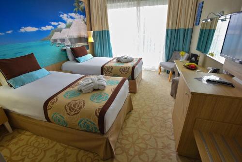 a hotel room with two beds and a television at Hotel Izgrev Spa & Aquapark in Struga