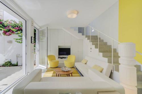 a living room with a white couch and yellow chairs at Casa Trindade, encanto no coração de Tavira in Tavira