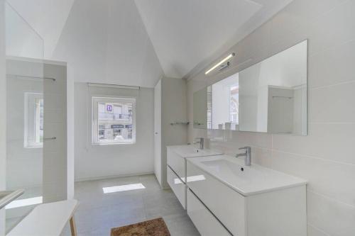une salle de bain blanche avec deux lavabos et un miroir dans l'établissement Casa Trindade, encanto no coração de Tavira, à Tavira