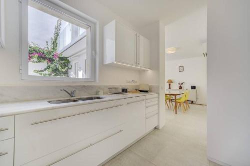 a white kitchen with a sink and a window at Casa Trindade, encanto no coração de Tavira in Tavira