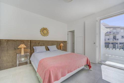 une chambre avec un grand lit et une grande fenêtre dans l'établissement Casa Trindade, encanto no coração de Tavira, à Tavira