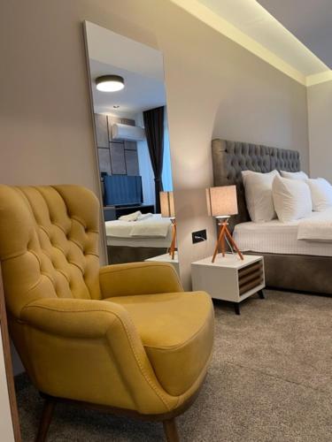 a bedroom with a yellow chair and a bed at Hotel & Restaurant Ponte Bianco in Vranje