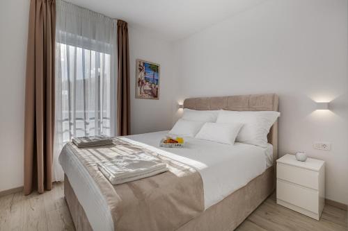 a white bedroom with a large bed and a window at Apartments Corcovado in Vodice