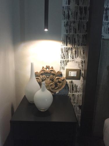 two white vases on a black table with a light at Addler House Apt by Addler House Ospitality in Mestre