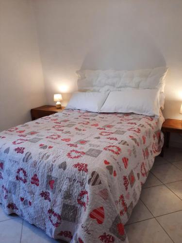 um quarto com uma cama com uma colcha vermelha e branca em Foresteria Guest House em Gaiole in Chianti