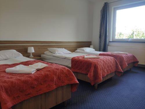 Habitación con 2 camas con sábanas rojas y ventana en Hotel Eden, en Rzgow