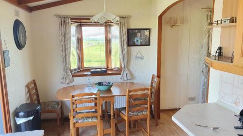 a dining room with a table and chairs and a window at Huntersfield Chalet in Faringdon