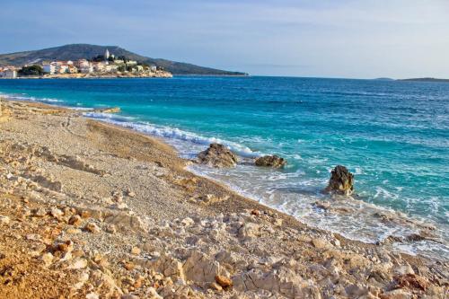a rocky beach with the ocean and buildings in the background at Holiday Home Primosten (54) in Primošten