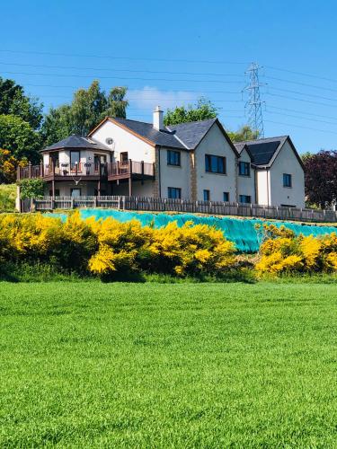 a house on a hill with a field of grass at Doura Lodge in Inverness